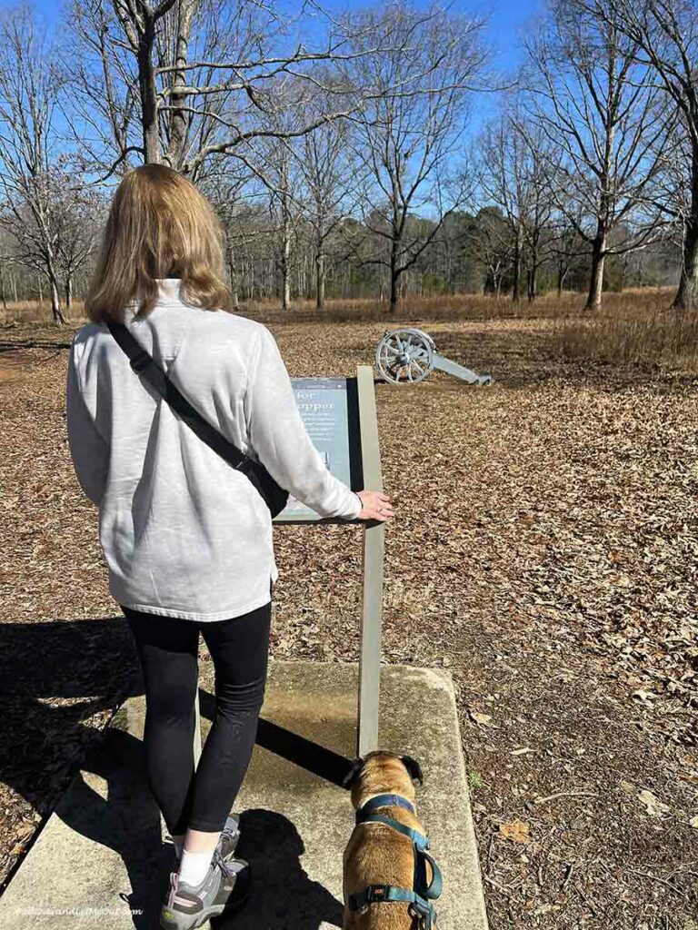 a woman and her dog in front of a Revolutionary war cannon