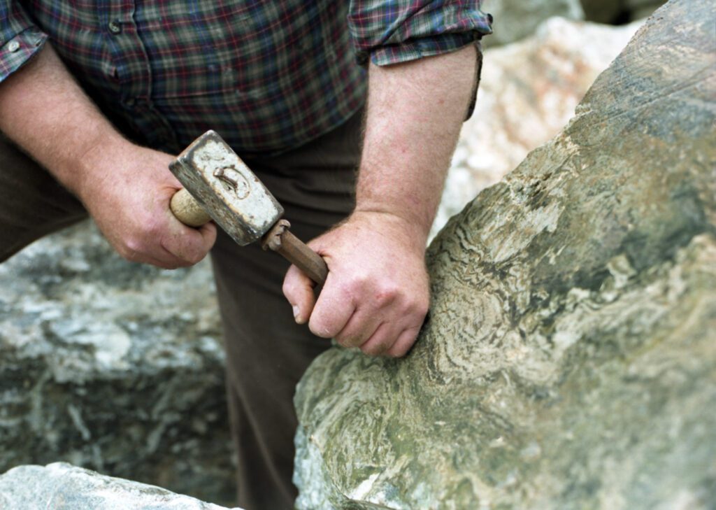 a man with a chisel working on marble