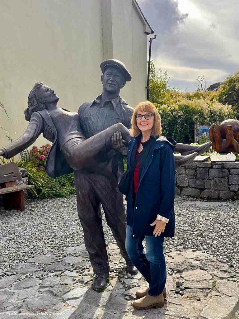 a woman standing next to a Quiet Man statue in Ireland